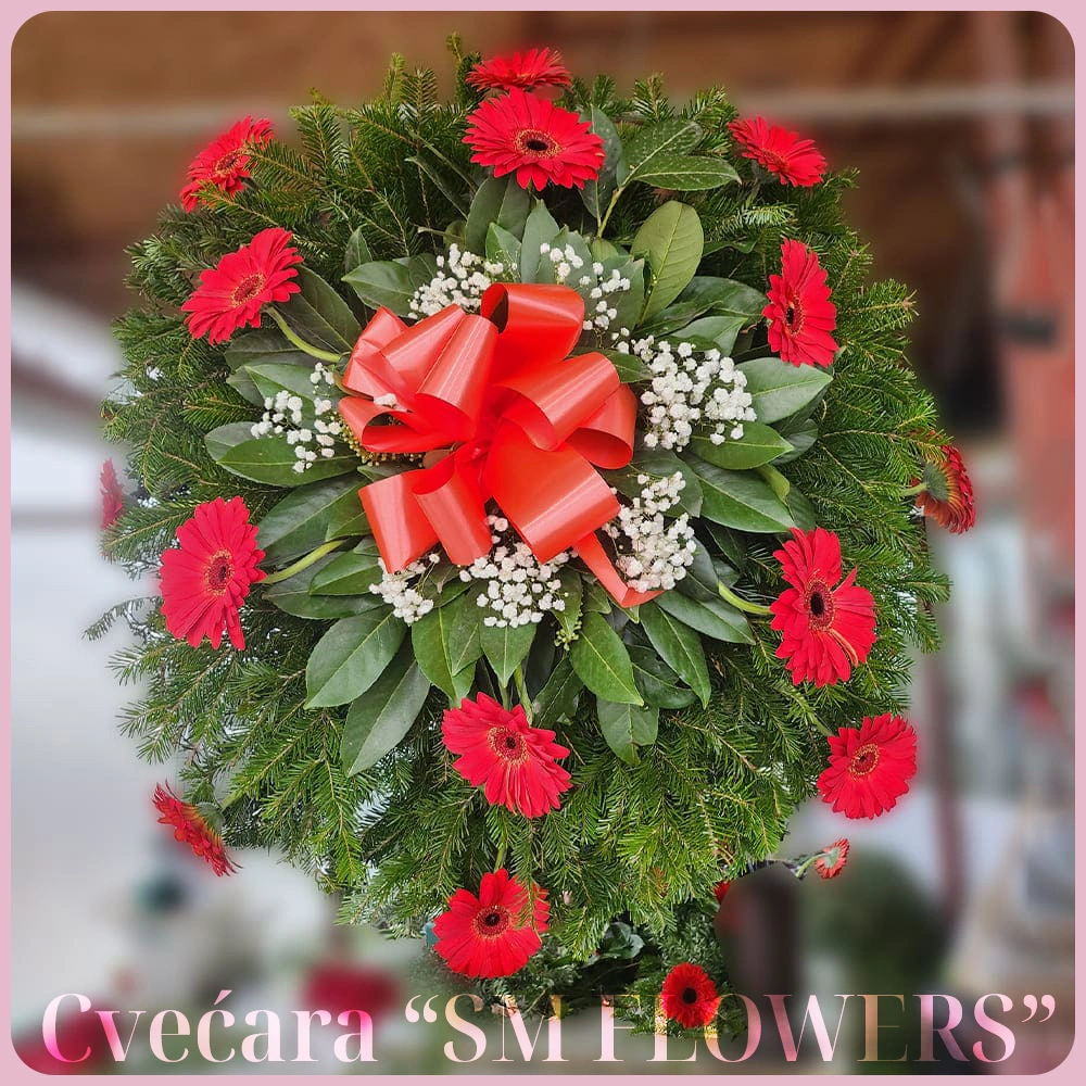 okrugli pogrebni venac sa crvenim gerberima i crvenom mašnom